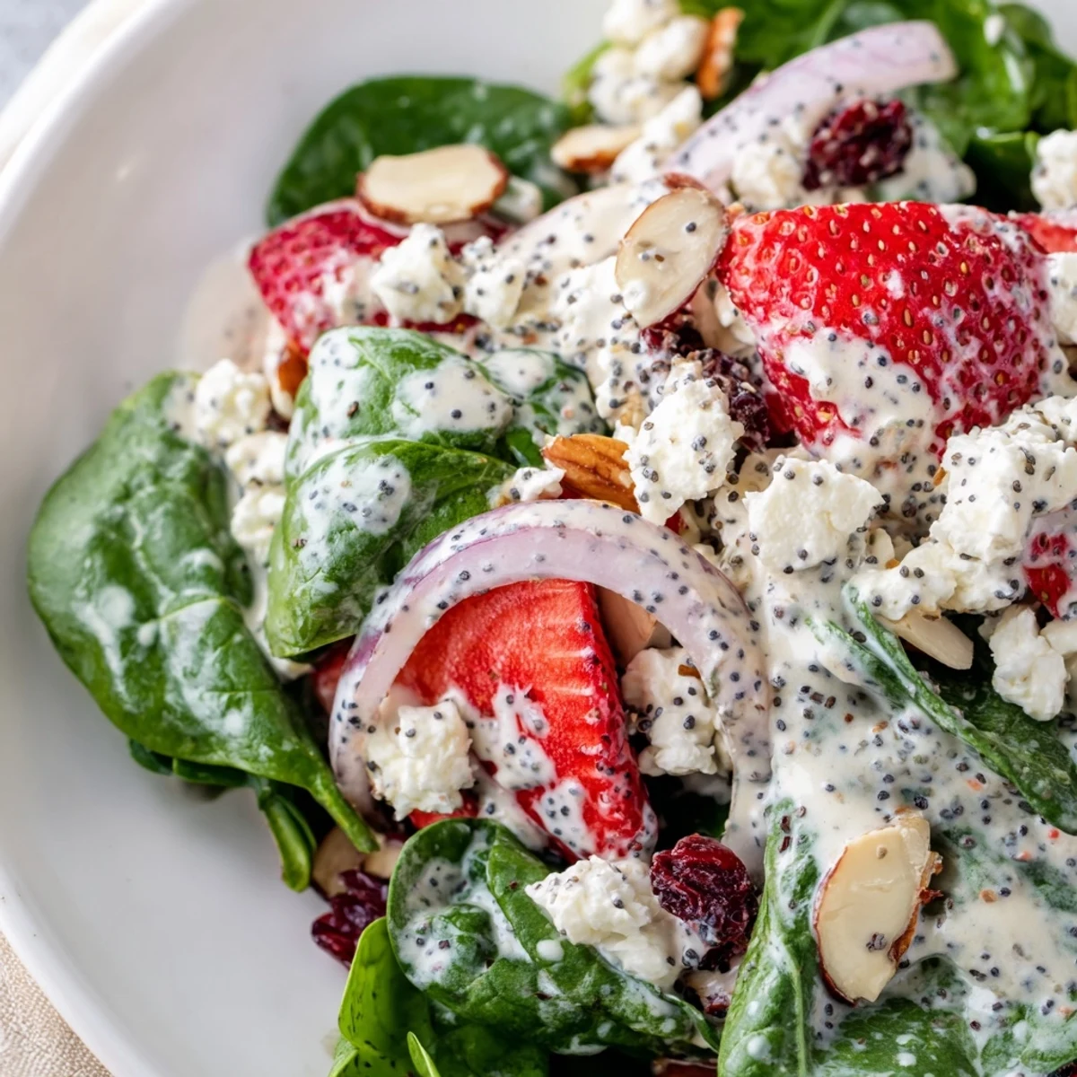 Fresh baby spinach and sliced strawberries topped with feta and almonds for a vibrant Strawberry Spinach Salad with Poppy Seed Dressing.