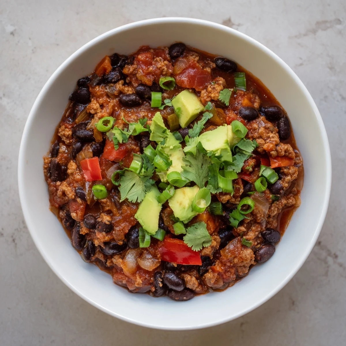 Hearty Turkey Chili with Black Beans simmering in a Dutch oven, showcasing tender ground turkey, black beans, and red bell peppers in a rich tomato broth.