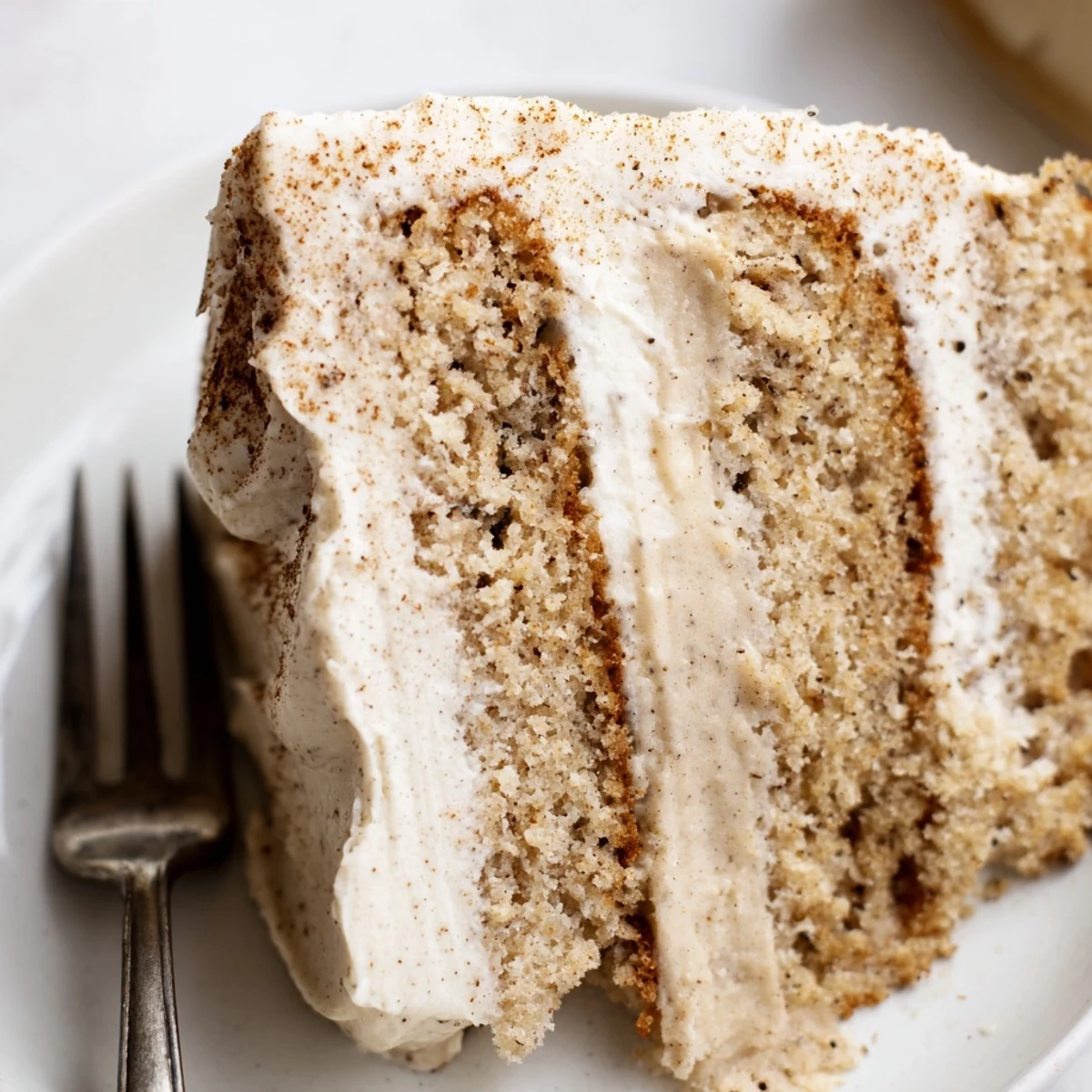 Close-up of Spiced Chai Latte Cake showcasing fluffy layers and a generous swirl of cream cheese frosting.