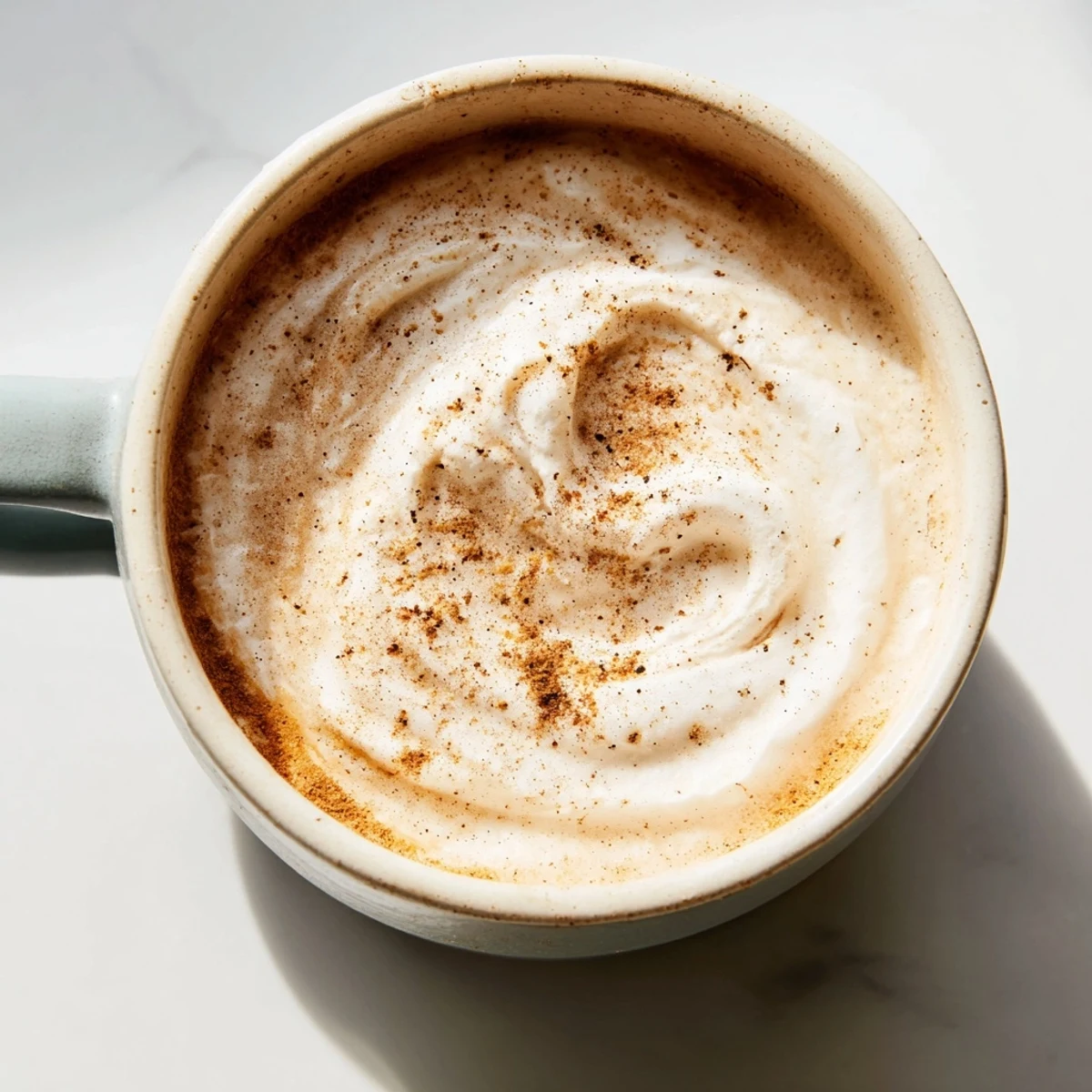 A warm mug of spiced cinnamon drink with cinnamon sticks and star anise, served as a cozy festive beverage.