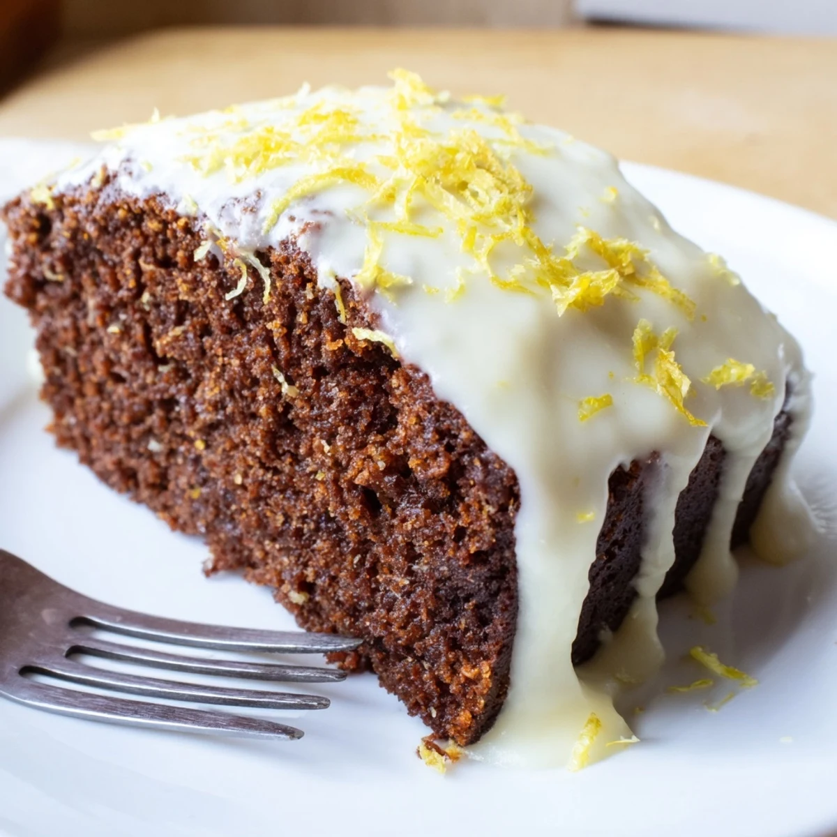 Freshly baked Gingerbread Loaf with Lemon Cream Cheese Glaze on a rustic wooden cutting board, drizzle dripping down the side.