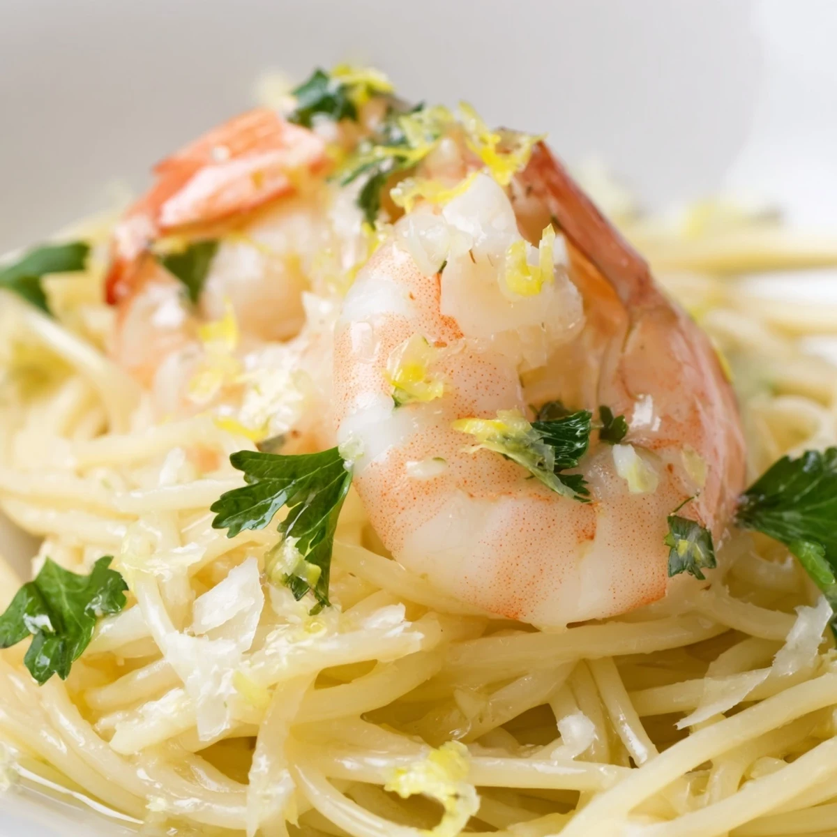 A plated portion of Lemon Shrimp Pasta garnished with parsley, with a glass of white wine and crusty bread nearby.