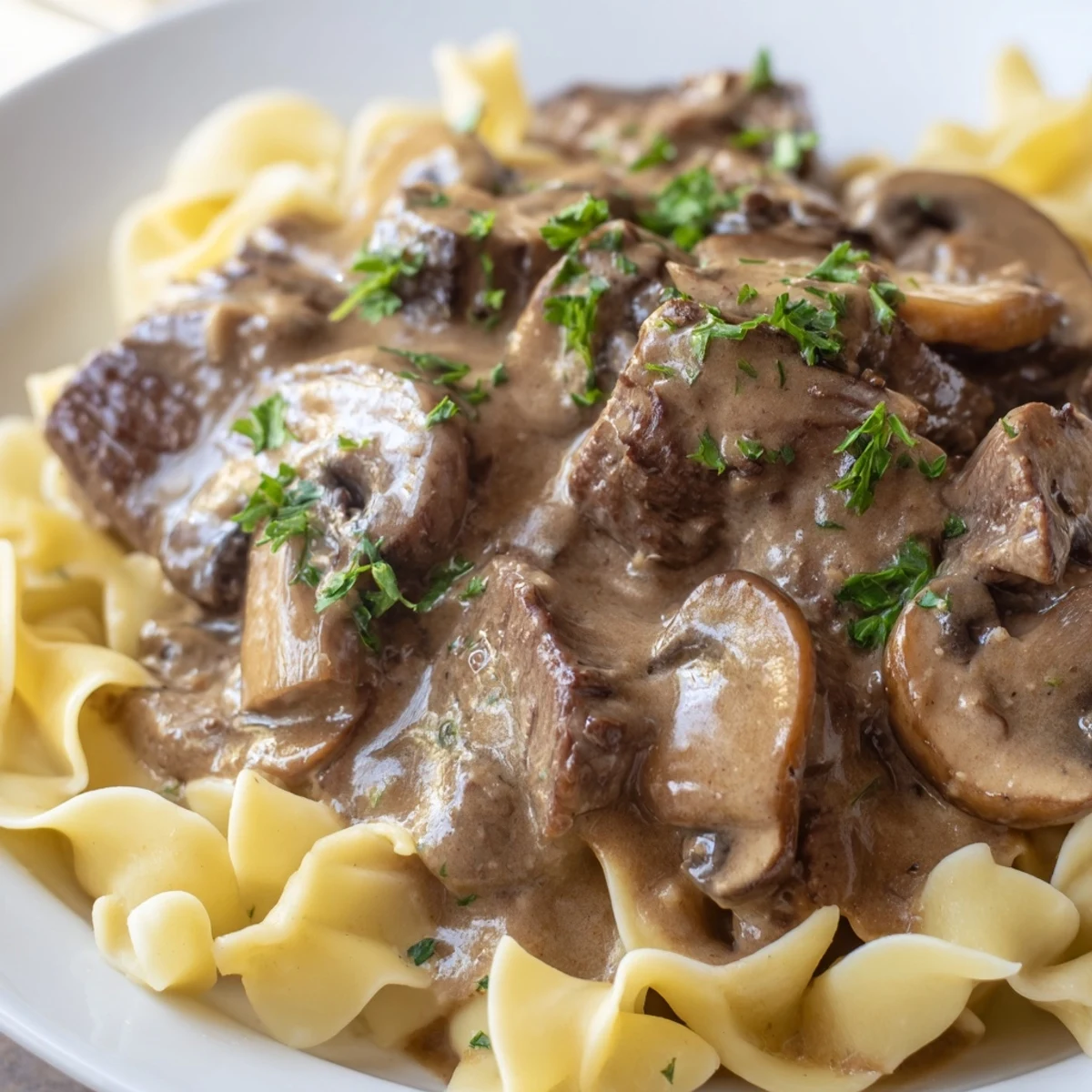 Creamy beef stroganoff with tender beef strips and mushrooms served over a bed of egg noodles.