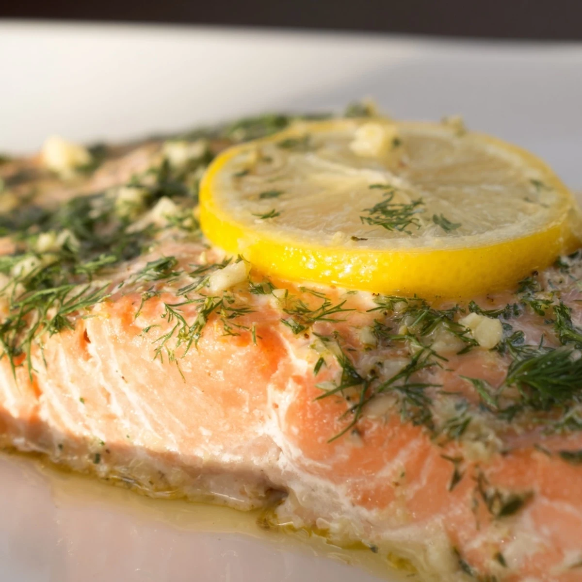 Golden-brown Baked Salmon with Lemon and Dill Weed on a baking sheet, garnished with fresh herbs and lemon slices.