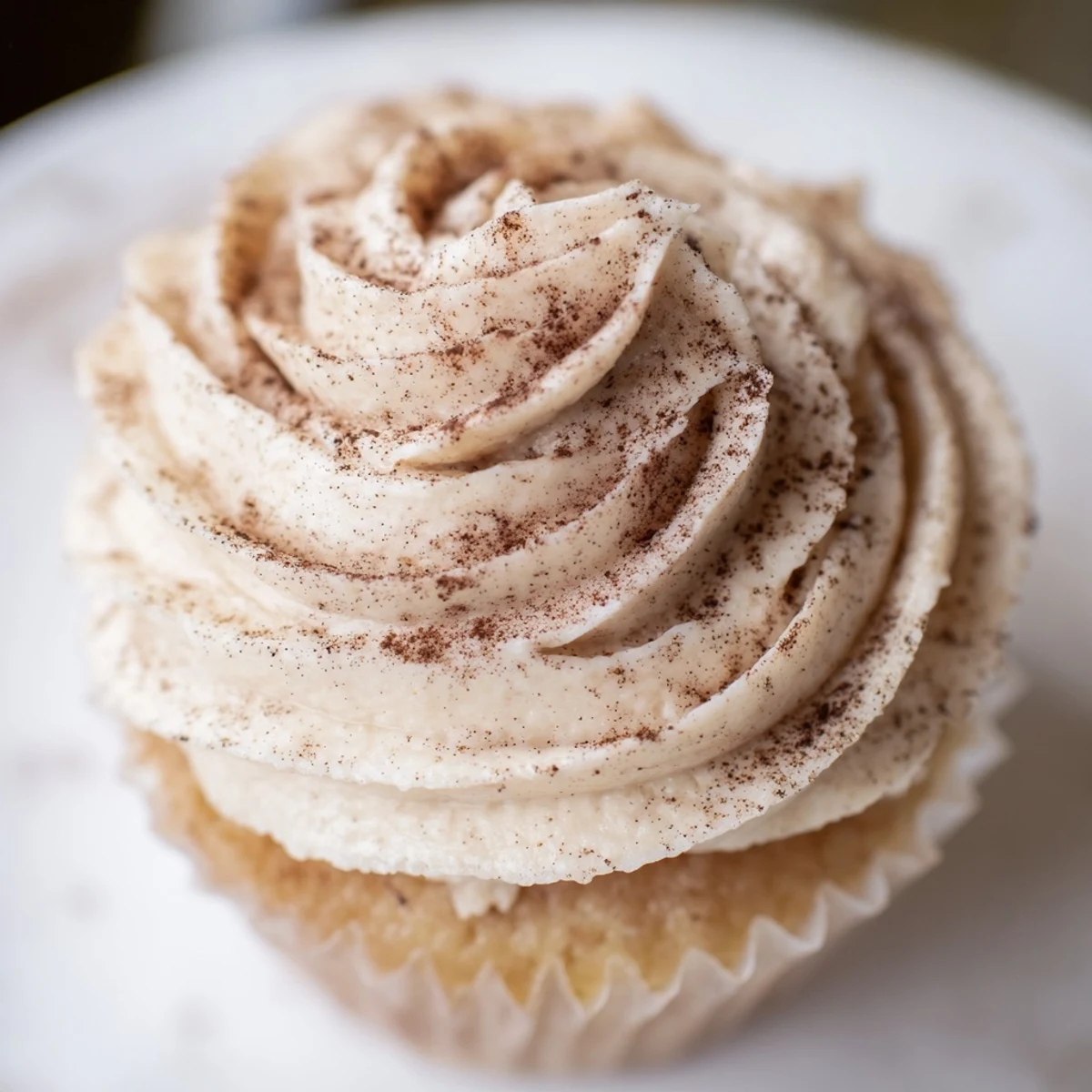 A close-up of frosted Irish Cream Cupcakes with rich buttercream swirls and a light dusting of cocoa powder on a rustic wooden board.  