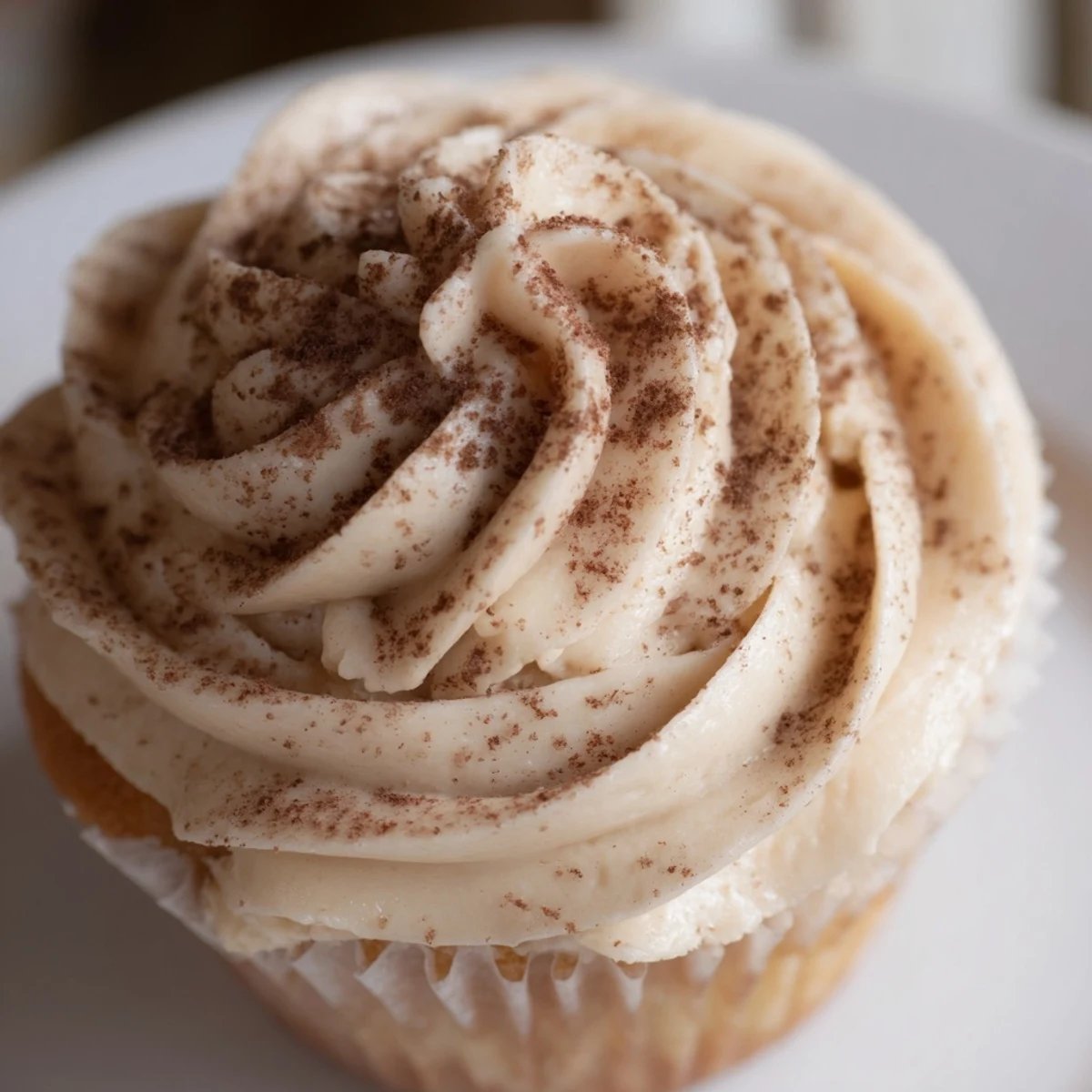 Stack of Irish Cream Cupcakes with velvety frosting, garnished with chocolate shavings and served on a vintage dessert plate.
