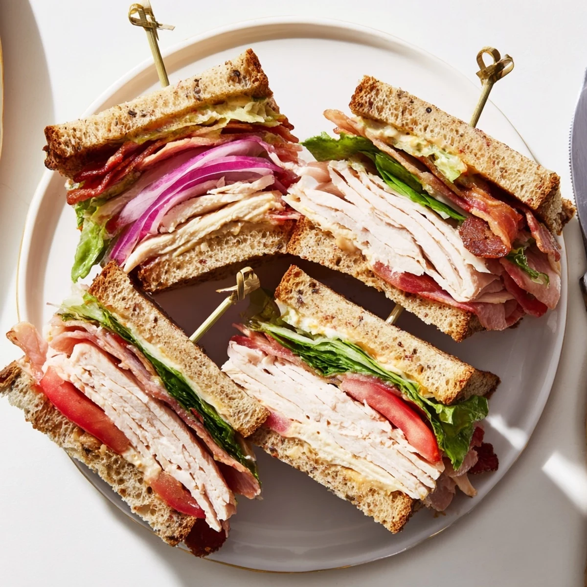 Golden toasted bread layers with roasted turkey, crisp turkey bacon, fresh lettuce, and juicy tomato slices, held together with creamy mayonnaise.