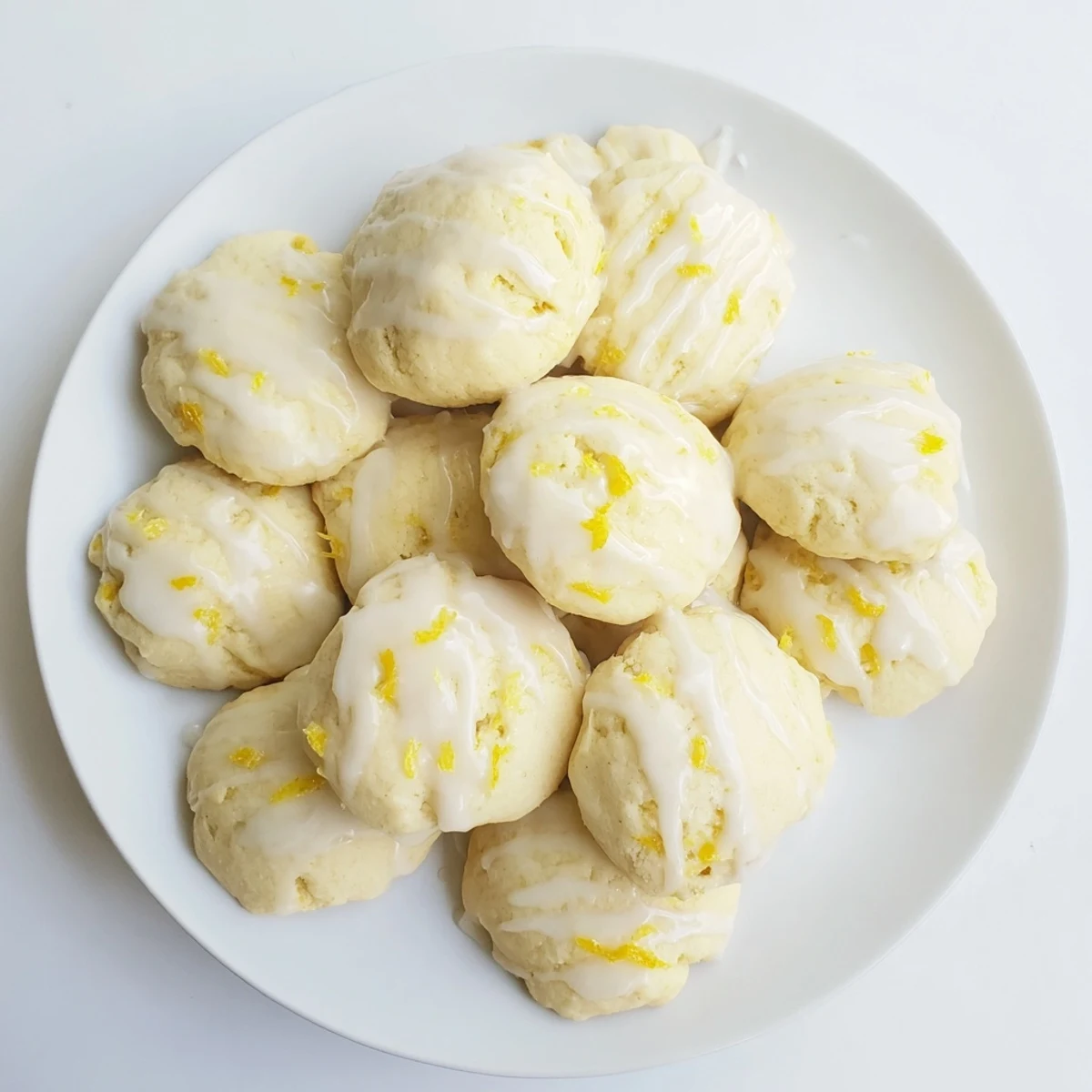 A spoon drizzling a bright lemon glaze over freshly baked Lemon Ricotta Cookies, highlighting the moist, tender crumb and tangy citrus aroma.