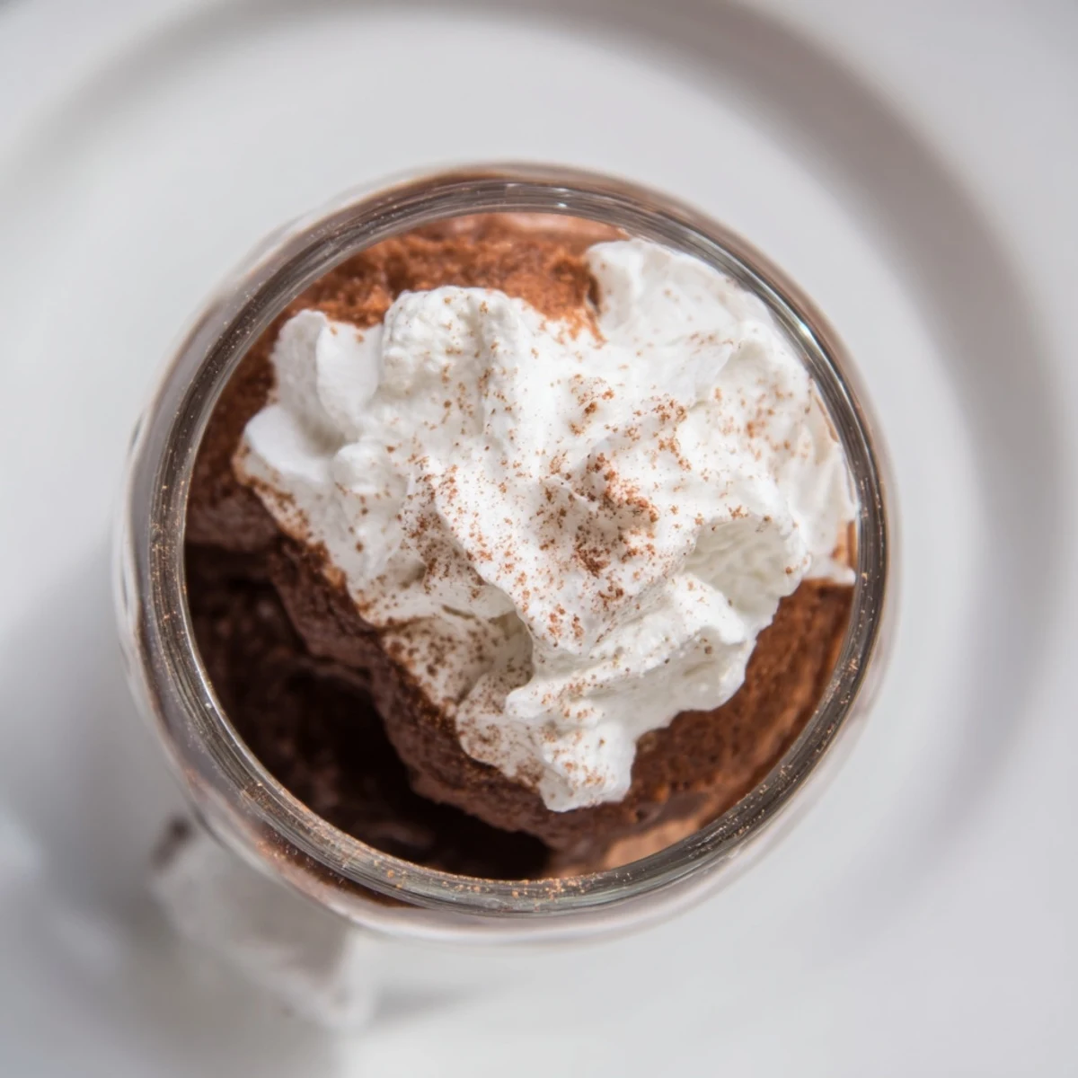 Rich chocolate mousse dessert layered with velvety whipped cream, garnished with cocoa powder for an elegant treat.