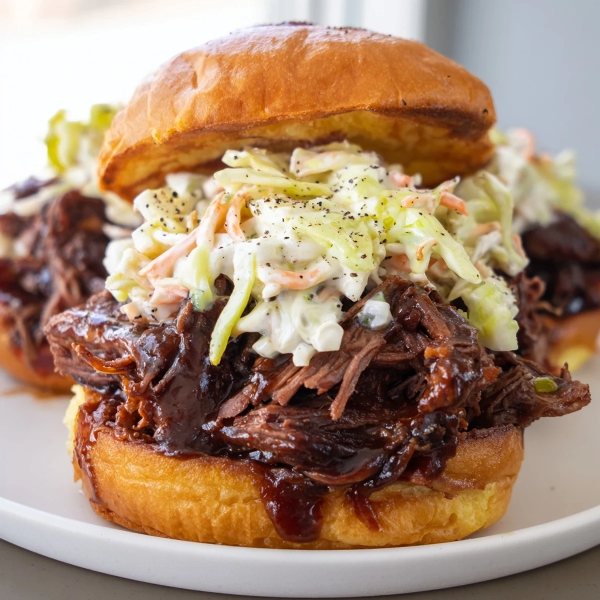 Shredded beef with tangy barbecue sauce and crunchy slaw on a soft bun, ready to serve.