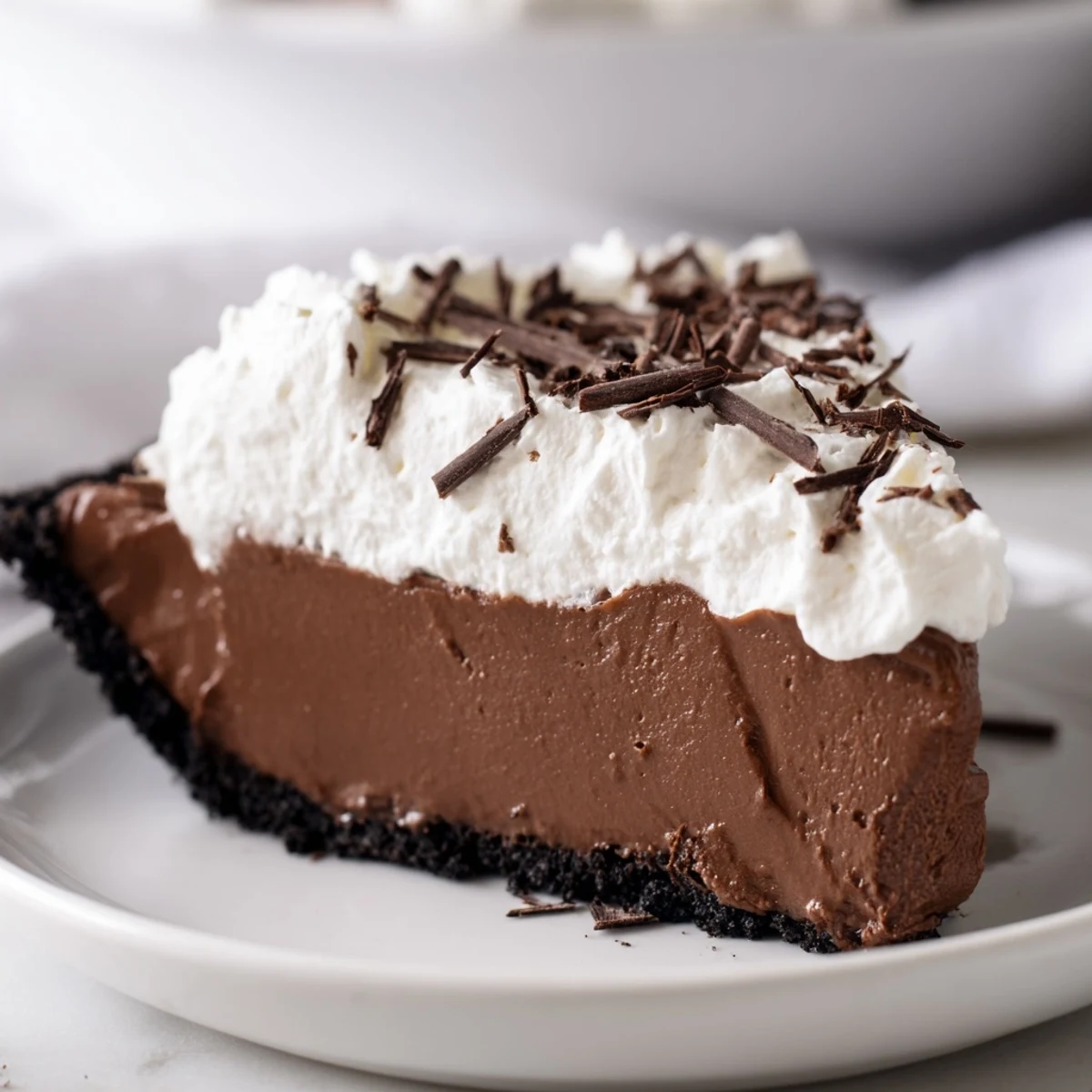 Fresh whipped cream swirls and chocolate shavings garnish the top of the chilled chocolate silk pie.  