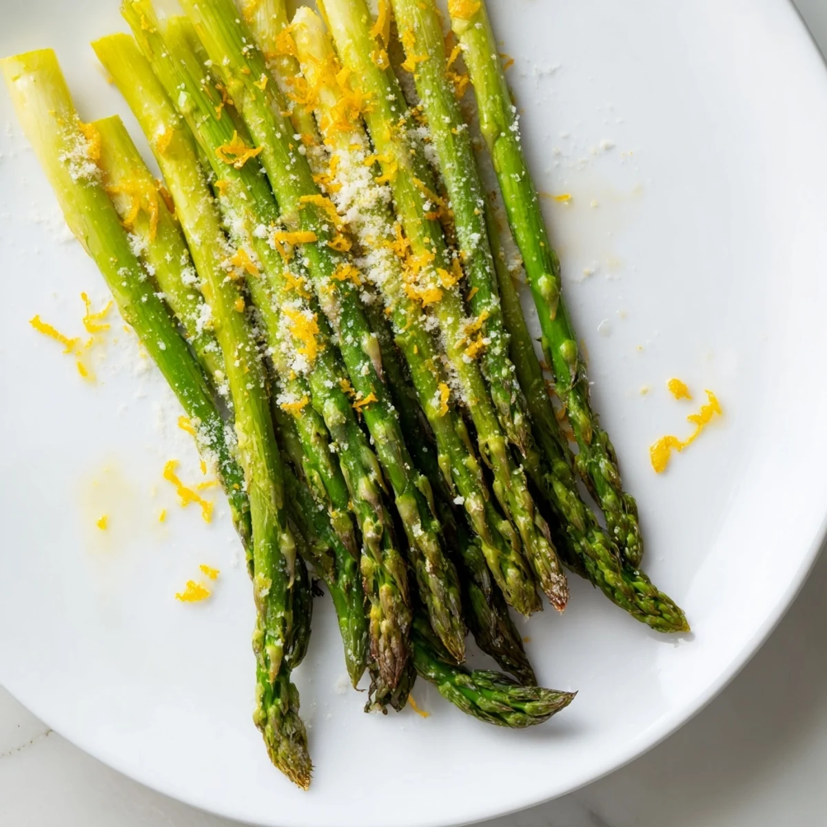 Golden-brown roasted asparagus with Parmesan and lemon zest on a baking sheet, ready to serve as a bright side dish.  