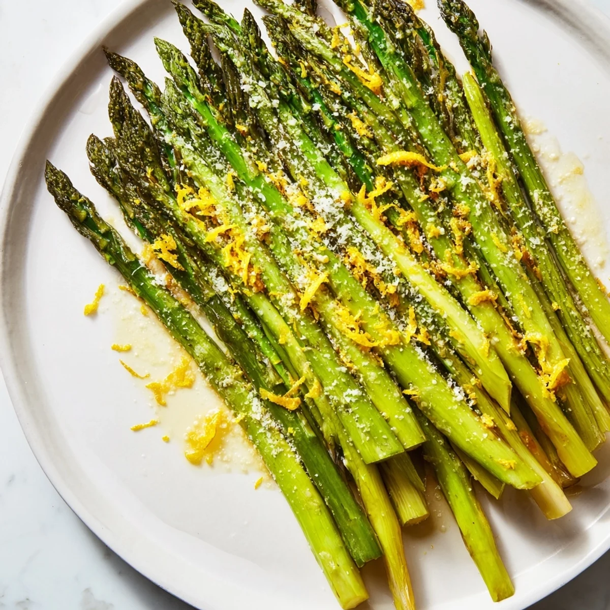 Tender roasted asparagus spears garnished with Parmesan and lemon, paired with grilled chicken for a Mediterranean meal.