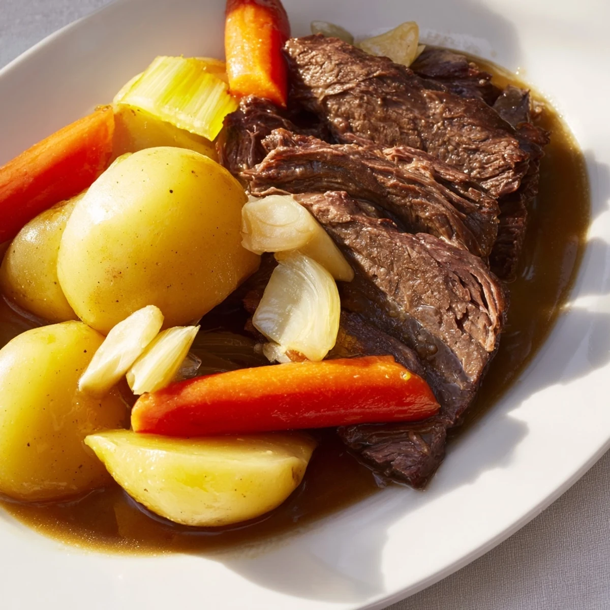 A serving of Slow Cooker Beef Pot Roast with Root Vegetables on a white platter, with tender shredded beef, carrots, parsnips, and potatoes drizzled with rich gravy.