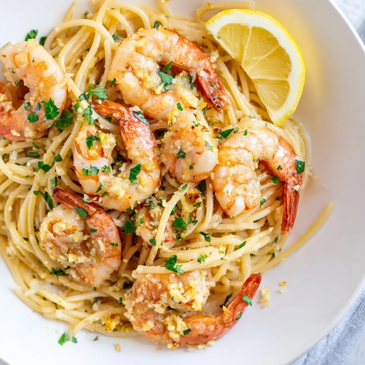 Steam rises from the skillet as succulent shrimp and pasta are tossed in a rich lemon garlic butter sauce, ready to be served on white dinner plates.