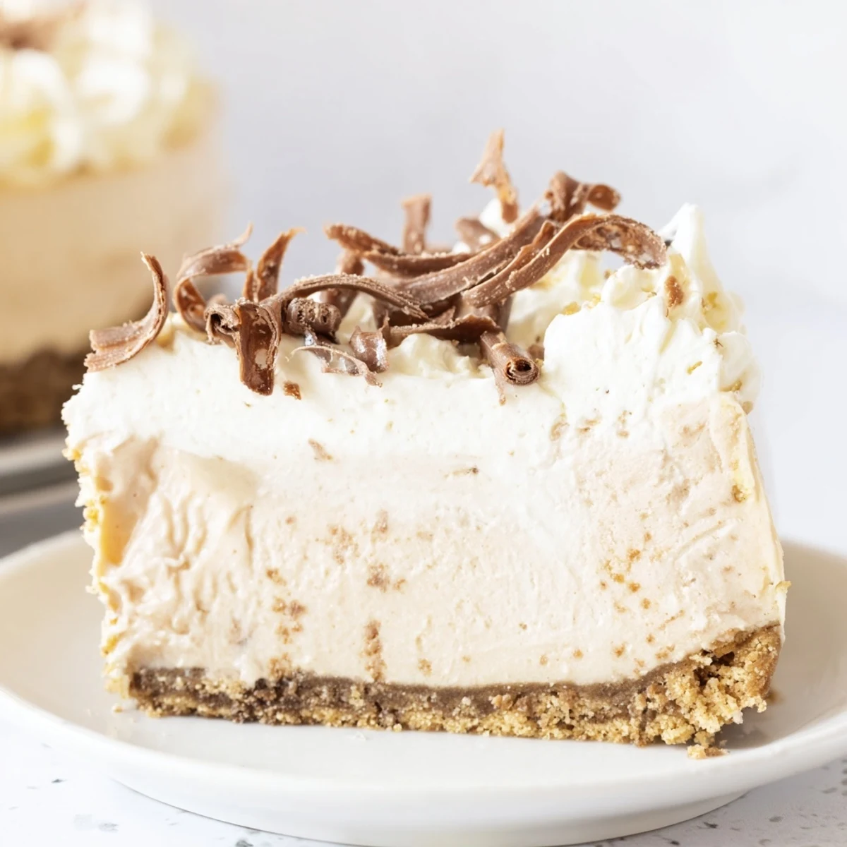 The creamy topped Irish Cream Cheesecake is presented on a marble counter, next to a steaming cup of coffee for a perfect pairing.