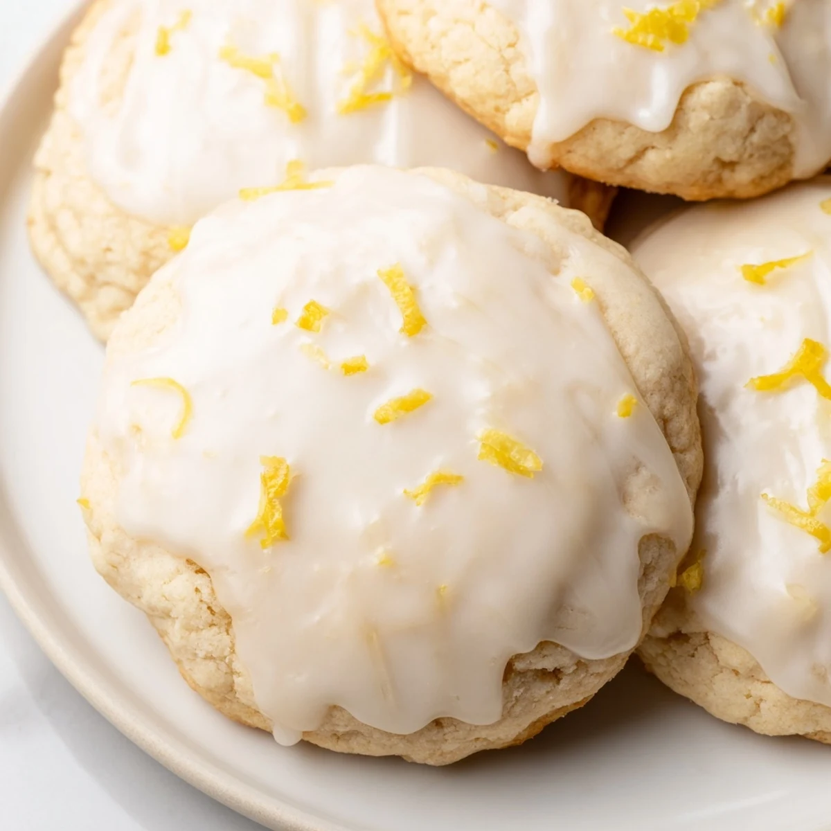 Golden-baked Lemon Ricotta Cookies with Lemon Glaze sit on a wire rack, glistening with sweet glaze and sprinkled with fresh lemon zest.