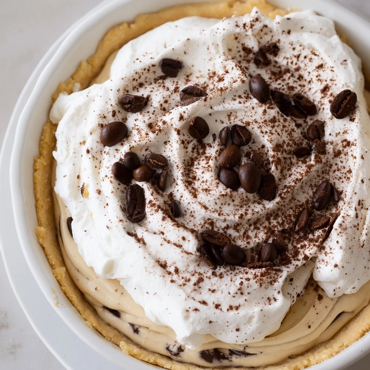 Creamy Keto Cold Brew Coffee Pie slice with almond flour crust, whipped cream topping, and visible coffee bean garnish on a marble plate.