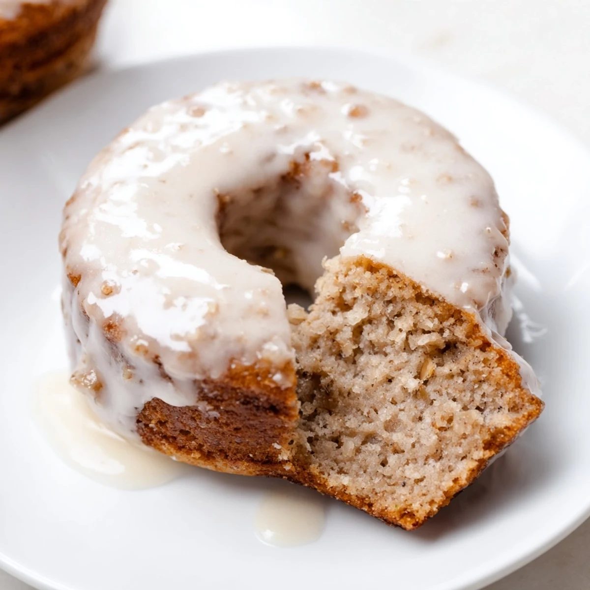 Warm Baked Banana Bread Donuts fresh from the oven, with a golden-brown crumb and a light drizzle of vanilla glaze on top.
