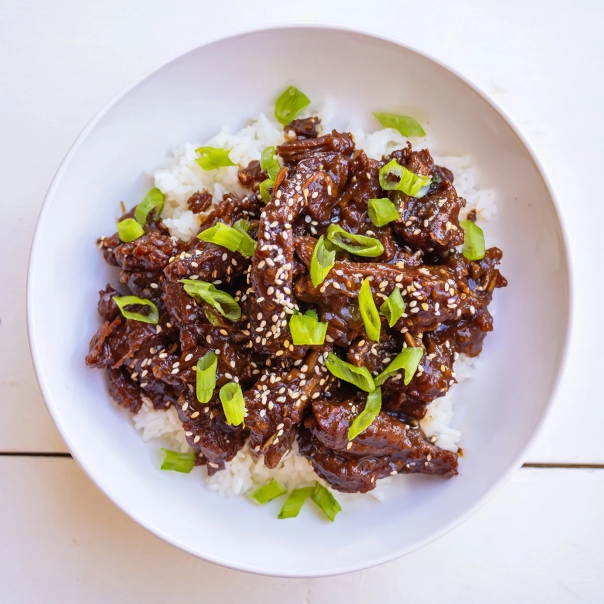 Crock Pot Korean Beef simmering in a glossy savory-sweet sauce, garnished with sesame seeds and scallions on fluffy rice.