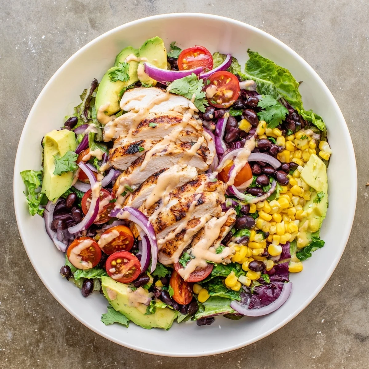 Serving suggestion for Chipotle Lime Chicken Salad with black beans, corn, and tangy lime dressing drizzled on top.