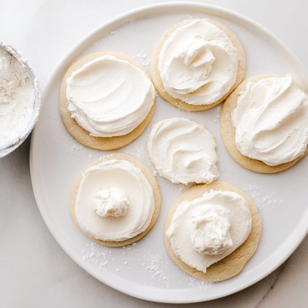 Easy Sugar Cookie Frosting in vibrant pink and blue, spread on round sugar cookies arranged on a rustic wooden board.