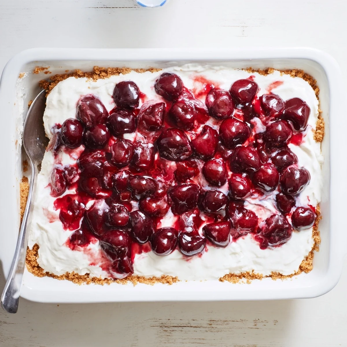 A spatula lifts a slice of Classic Cherry Delight, revealing the soft cream cheese filling and crumbly crust underneath.
