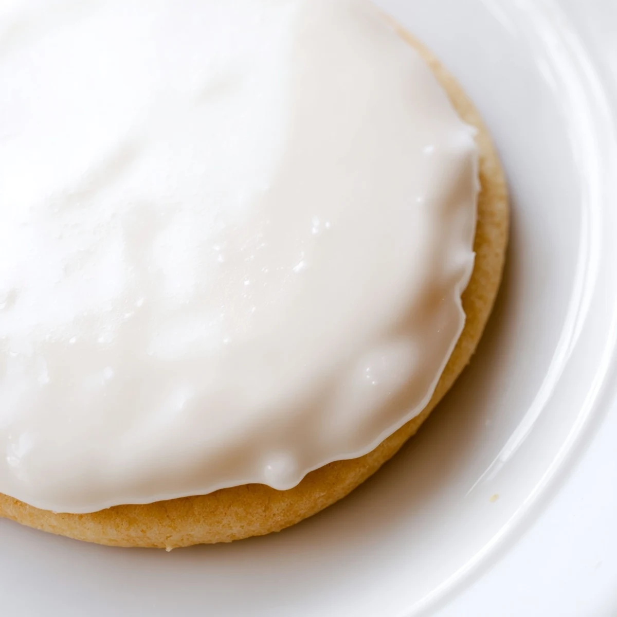 Glossy Sugar Cookie Icing drizzled over freshly baked round cookies with colorful sprinkles added for decoration.  