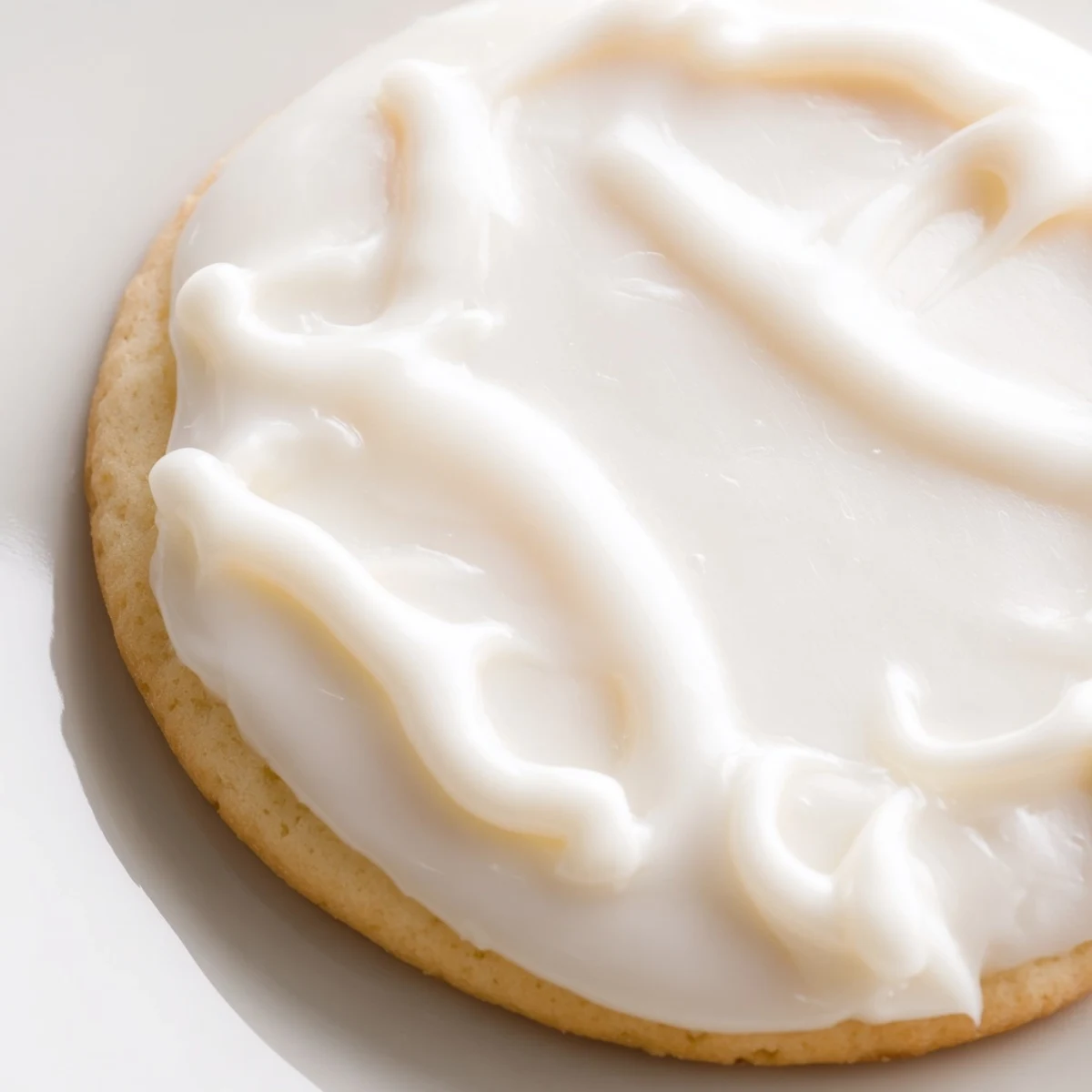 Vibrant red Sugar Cookie Icing being spread with a knife over gluten-free sugar cookies on a cooling rack.