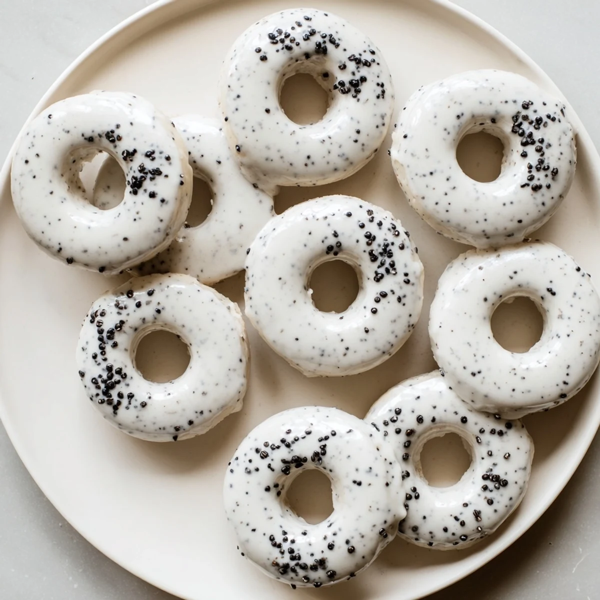 A stack of warm Black Sesame Mochi Donuts showing their chewy mochi texture and crisp exterior on a rustic wooden table.