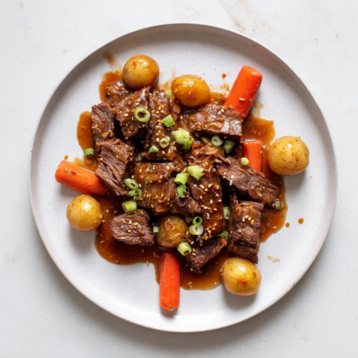 Sliced Slow Cooker Korean Beef Pot Roast drizzled with rich soy garlic gravy, garnished with scallions and sesame seeds on a platter.