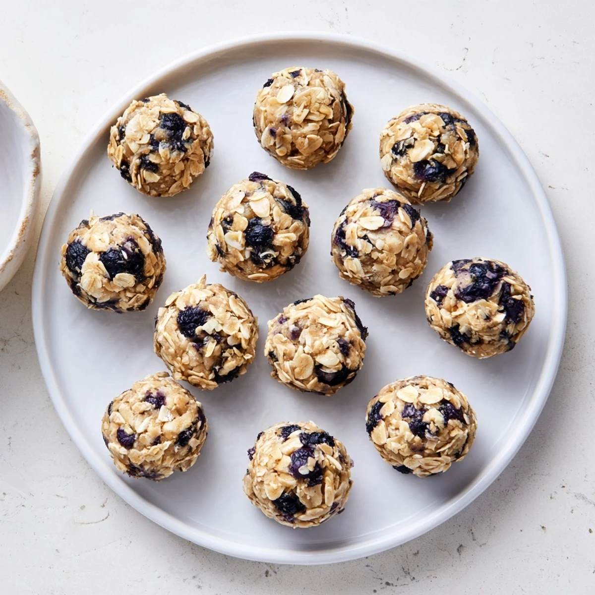 A close-up view of Blueberry Cheesecake Protein Bites highlights their creamy filling and rolled oats coating, perfect for post-workout energy.