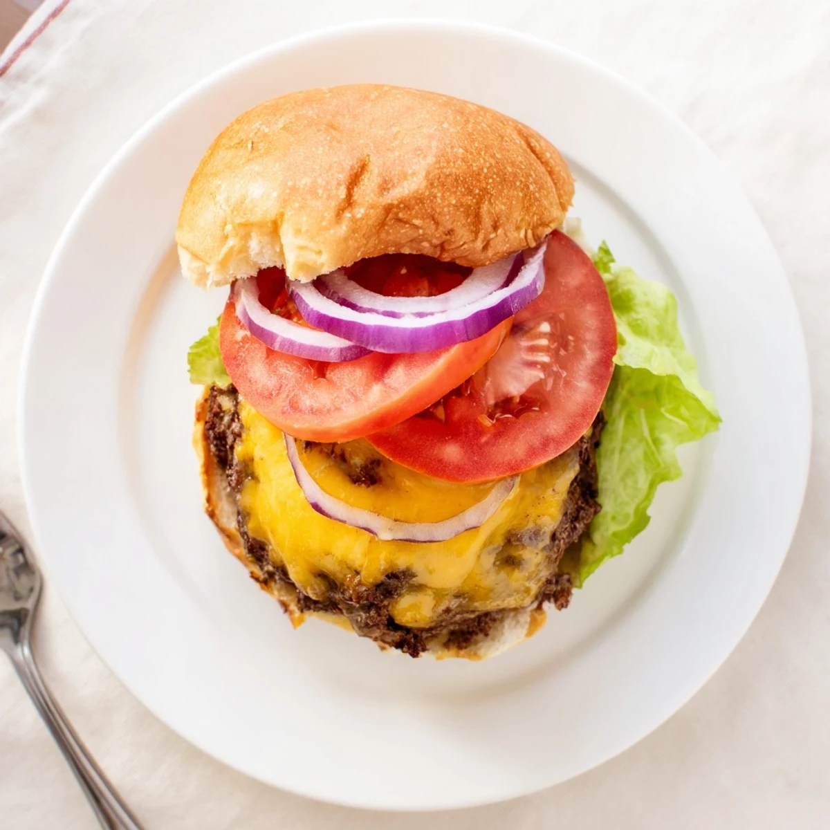 Classic American smash burger with caramelized beef edges, melty cheese slice, and ripe tomato garnish