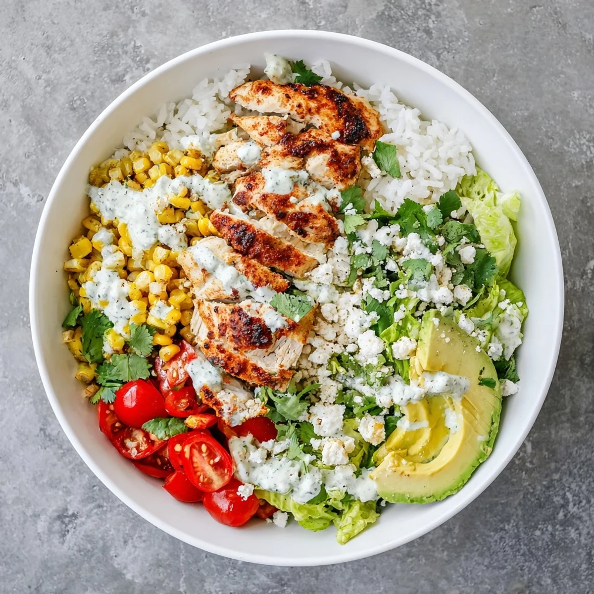 Colorful street corn chicken bowl featuring spiced grilled meat, charred corn kernels, crumbled cotija cheese, and creamy lime crema drizzle