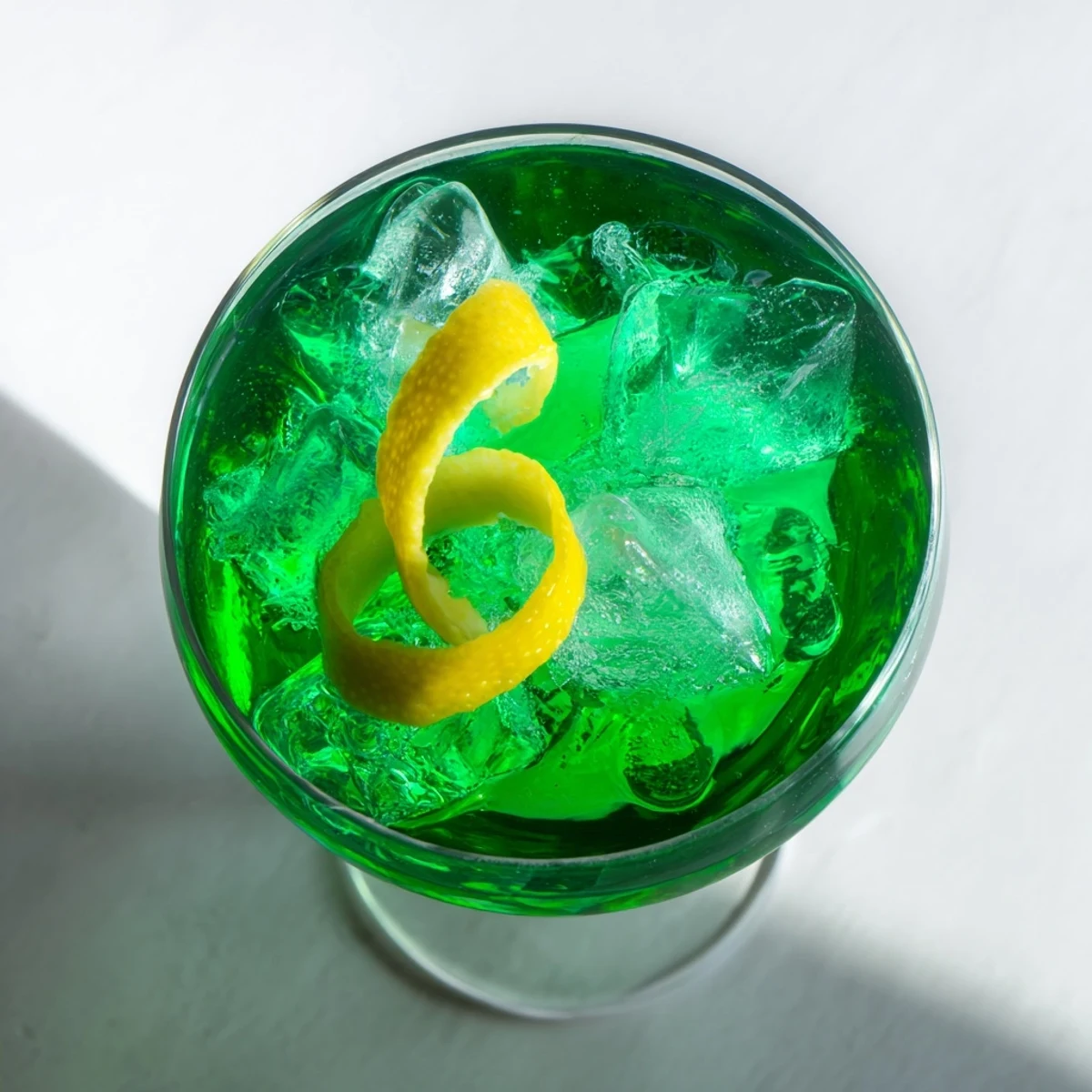 Emerald green Luck of the Irish cocktail with lemon twist on crystal rocks glass