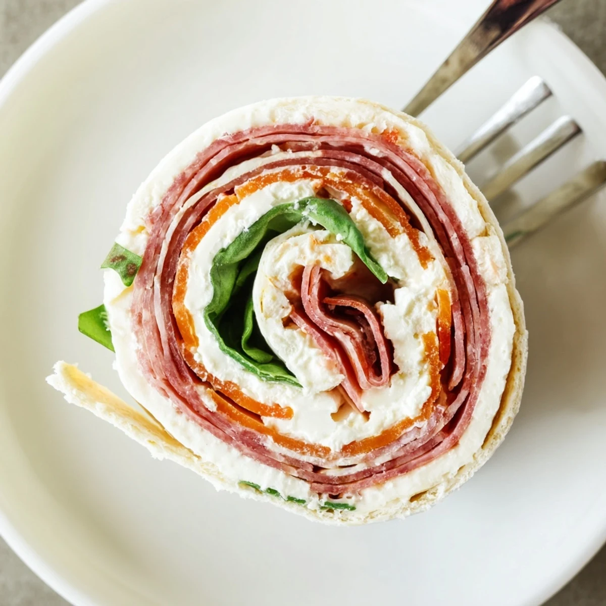 Colorful spiral of Italian pinwheels showcasing layers of salami, ham, and cream cheese filling