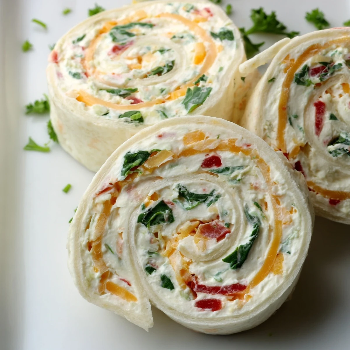 Golden spiral pinwheels featuring colorful vegetable specks in creamy cheese filling rolled inside soft flour tortillas