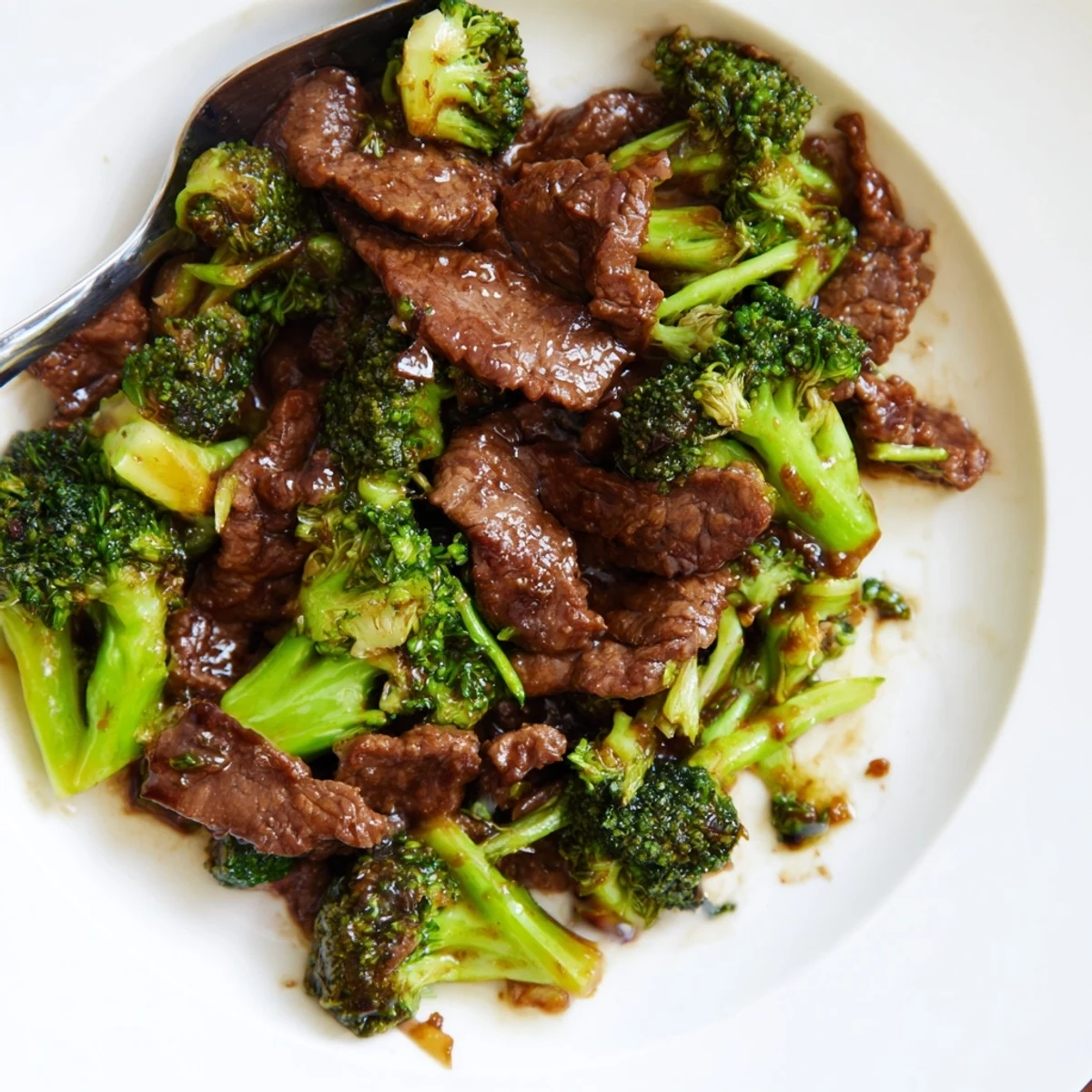 Homemade beef and broccoli stir fry sauce bubbles thickly in a wok, caramelizing crisp vegetables and juicy beef