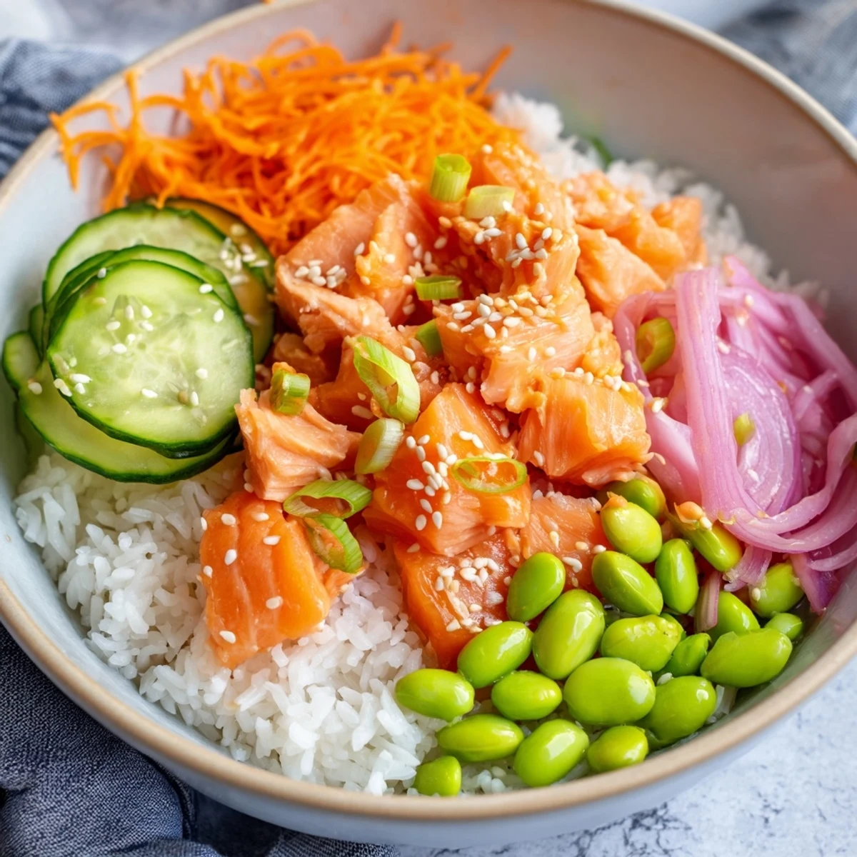 Close-up of tender baked salmon pieces atop a rice bowl with fresh vegetables and sesame seed garnish