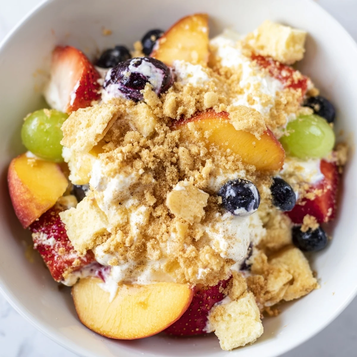 Refreshing peach cobbler cheesecake fruit salad bowl with fresh tropical fruit medley and spiced buttery crumble garnish