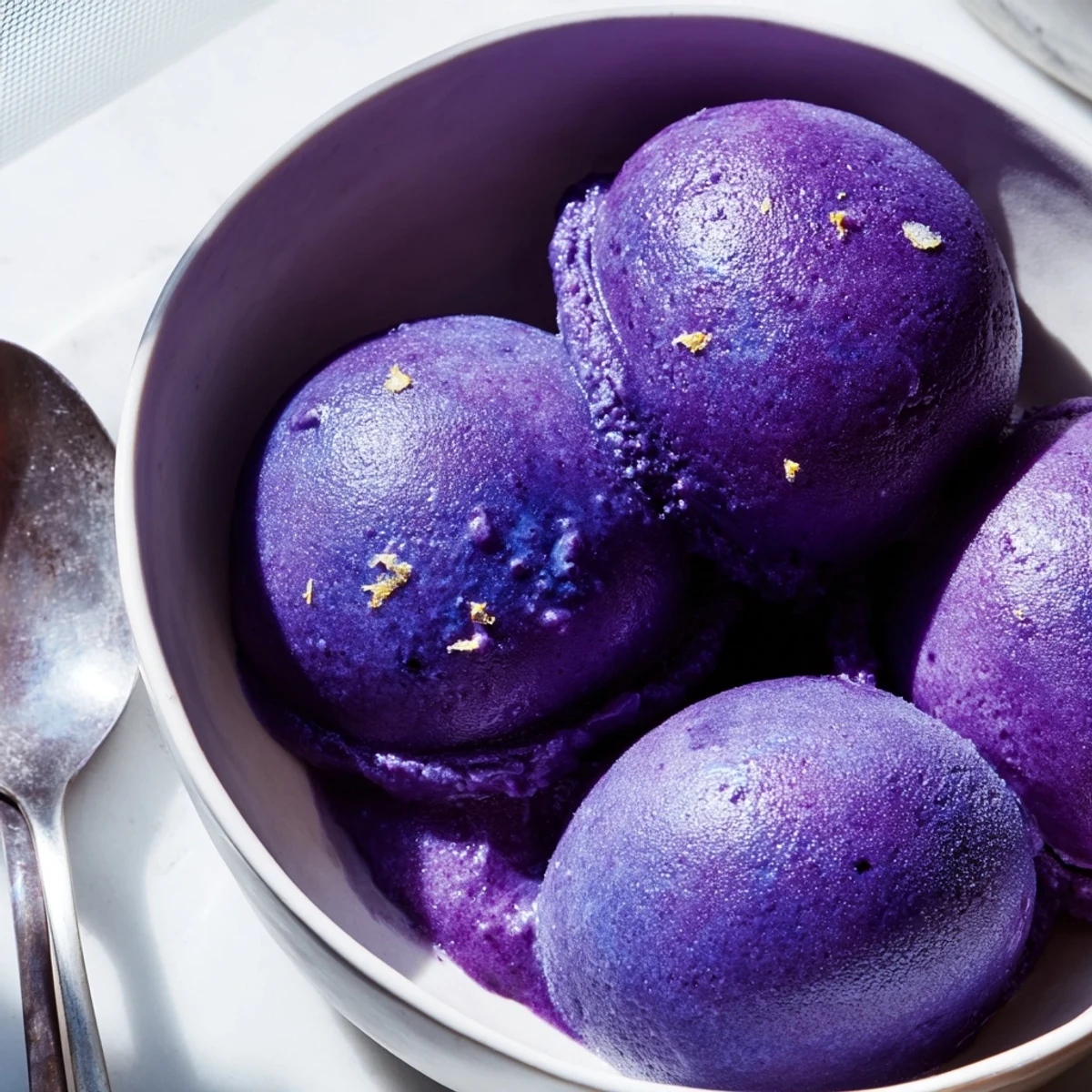 Creamy no churn blueberry lemon sorbet served in vintage dessert bowls with whole blueberries scattered around