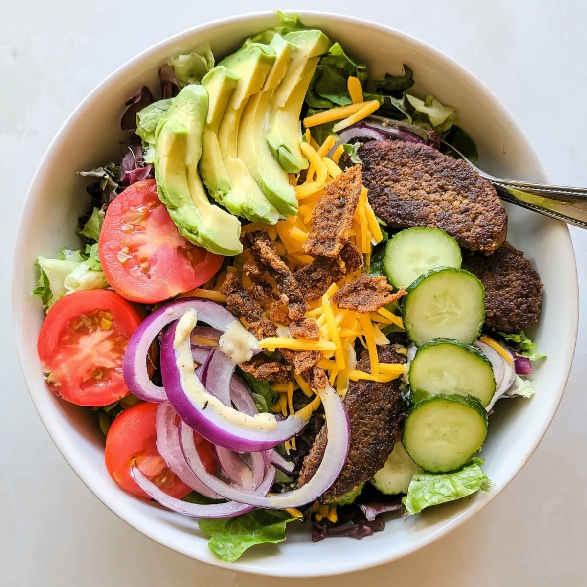 Low-carb smash burger bowl with crunchy fried onions, melted cheddar, and ripe avocado slices