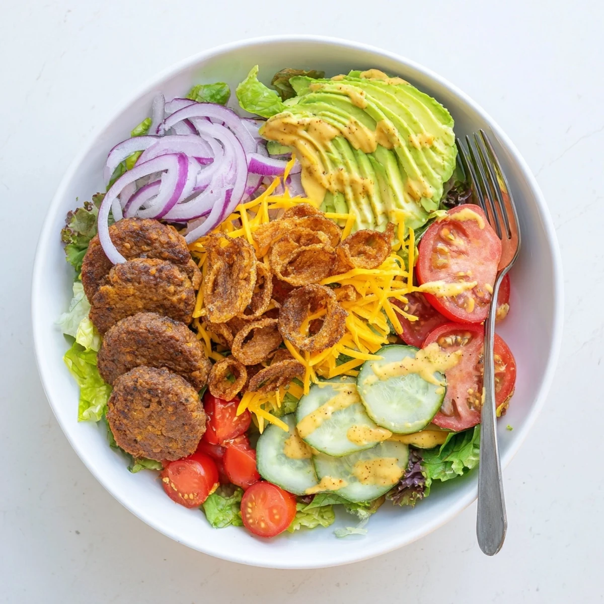 Deconstructed smash burger bowl featuring crispy beef, fresh vegetables, and drizzled special sauce