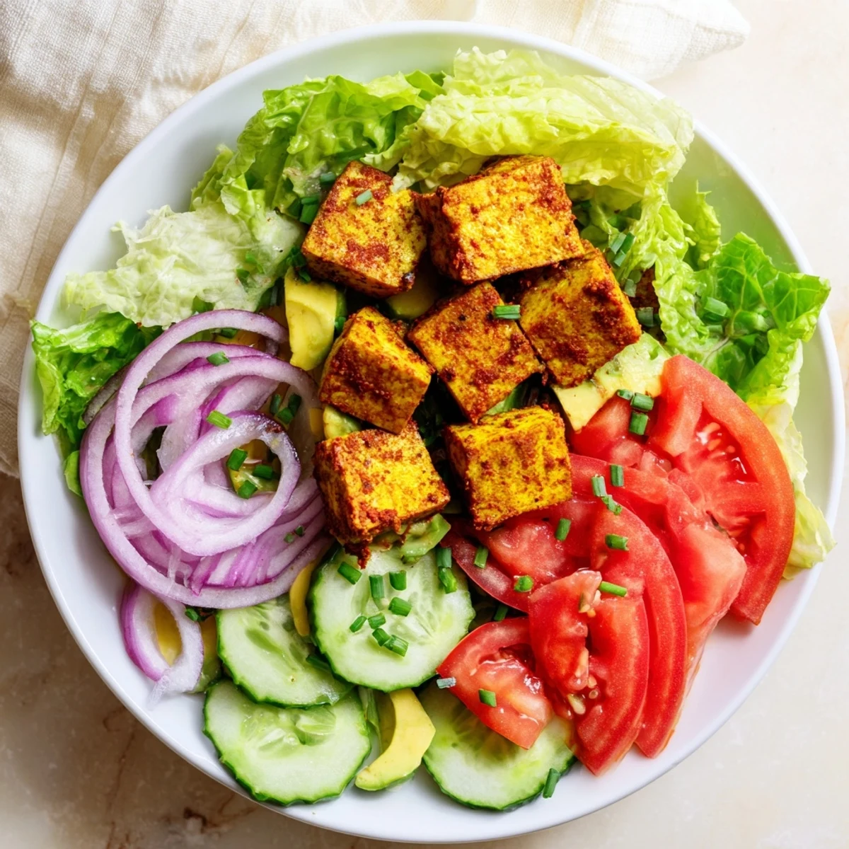 Fresh vegan salad featuring pan-fried smoky tofu, crunchy lettuce, and vibrant colorful summer vegetables
