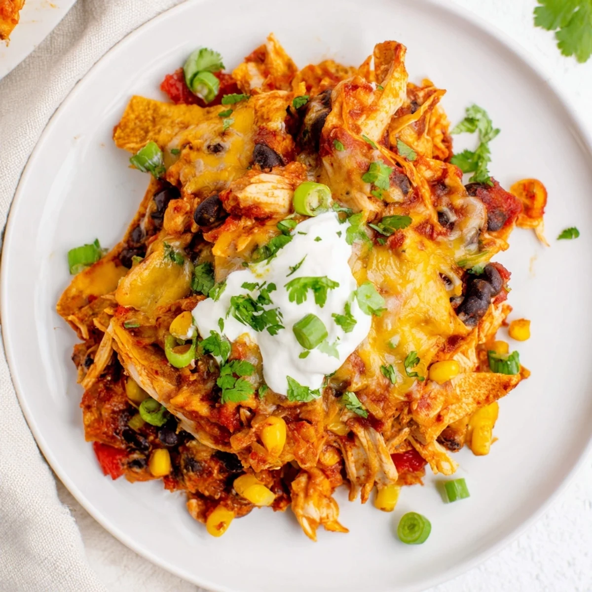 Layered Tex-Mex crockpot chicken enchilada casserole topped with shredded Mexican cheese and fresh cilantro
