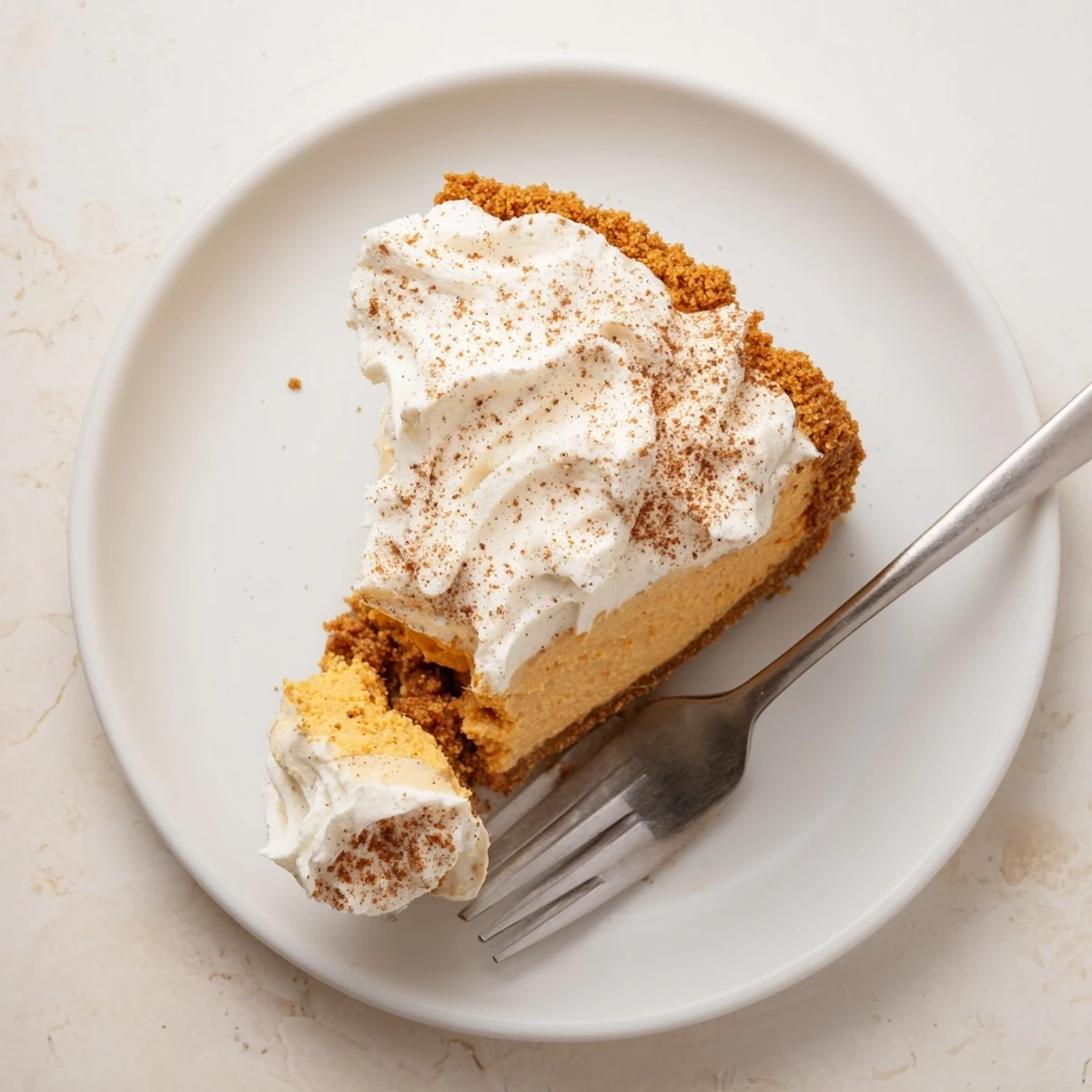 Festive pumpkin spice Christmas cheesecake topped with vanilla whipped cream and ground cinnamon on serving plate