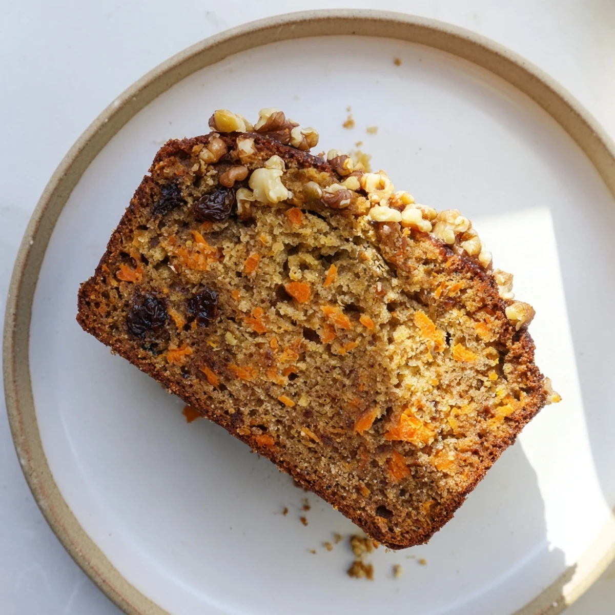 Homemade carrot cake banana bread cooling on wire rack, topped with optional chopped walnuts and raisins