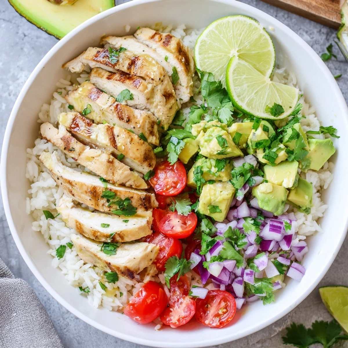 Golden Honey Lime Chicken Avocado Rice Stack plated with fresh cilantro and lime wedges on top