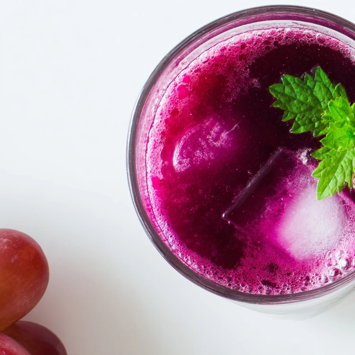 Grape Agua Fresca poured over ice with fresh mint and lime wedges