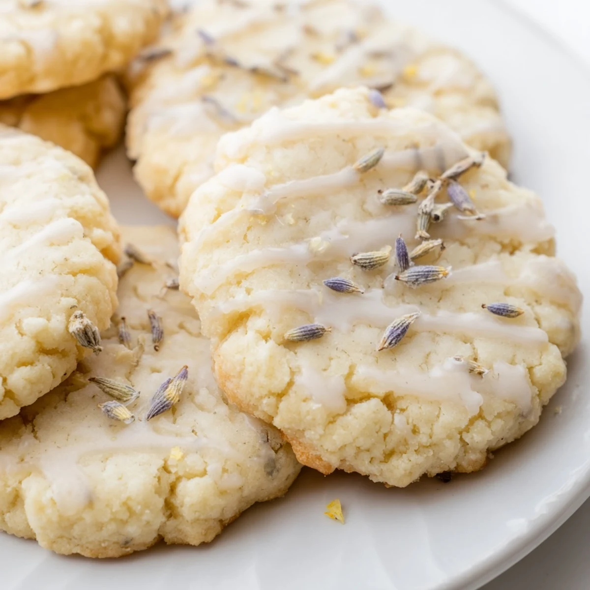 Soft Lemon Lavender Cookies with golden edges arranged on a rustic white ceramic plate